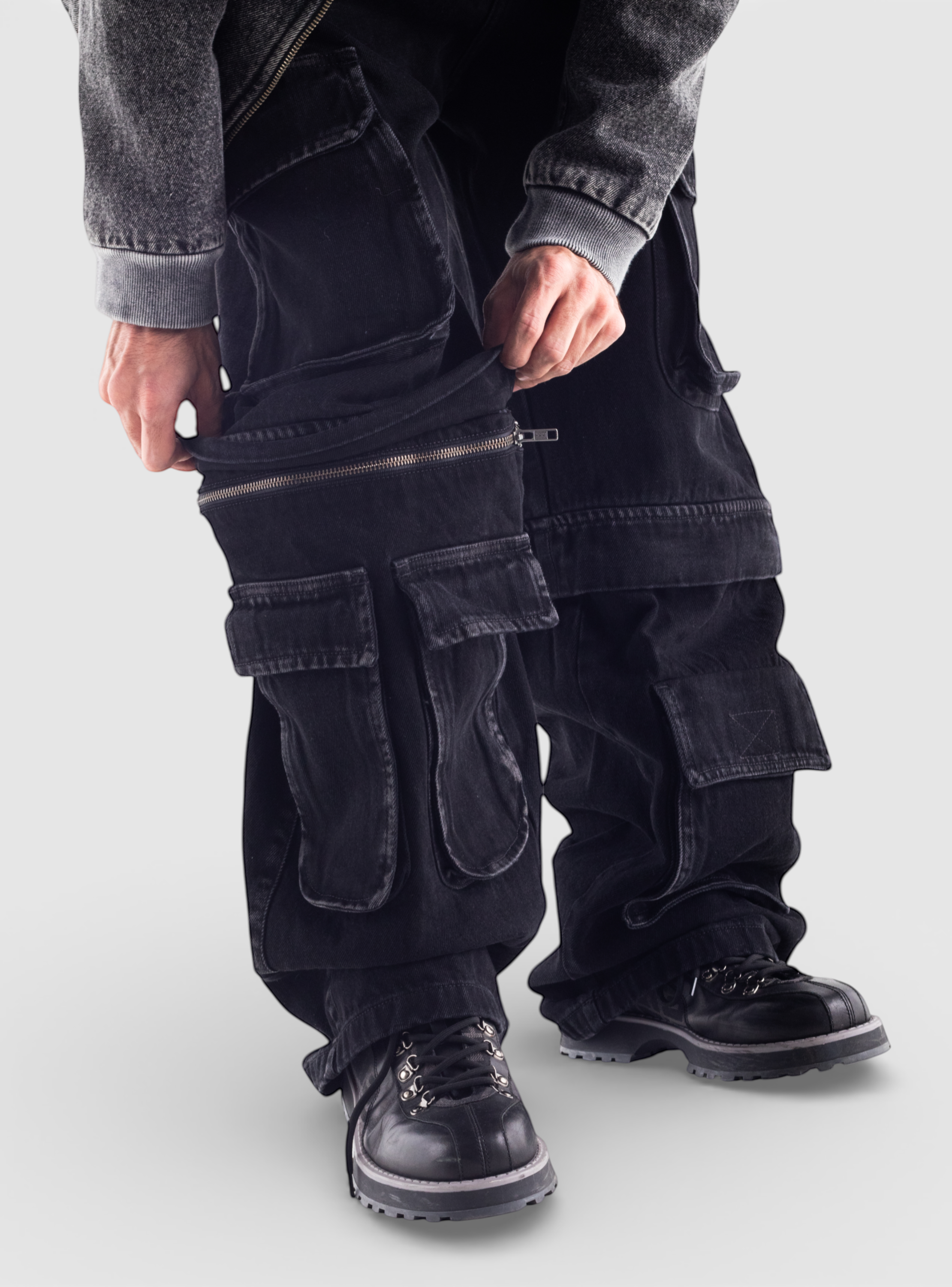 Fxckboy black denim utility relaxed fit jeans with multiple cargo pockets and zip-off legs, paired with black boots.